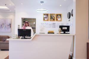 Un uomo in piedi dietro un bancone in una stanza di Quiet Dreams - Serviced Apartments Al-Nour Branch a Gedda