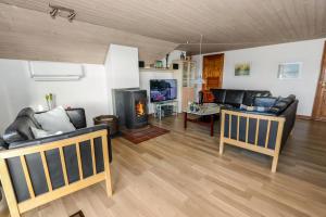 uma sala de estar com mobiliário de couro preto e uma lareira em Charming thatched stone house by the sea - SJ241 em Harboør