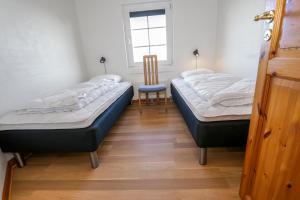 2 camas en una habitación con silla y ventana en Charming thatched stone house by the sea - SJ241 en Harboør