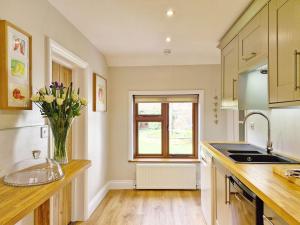 a kitchen with a sink and a vase of flowers on a counter at Walnut Cottage - Horsham in Horsham