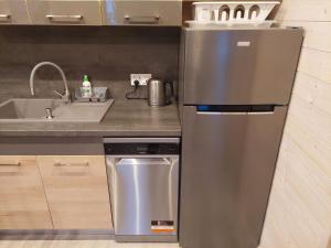a kitchen with a stainless steel refrigerator and a sink at BURSZTYNOWO Domy apartamentowe in Ostrowo