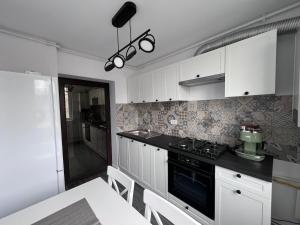 cocina con armarios blancos y estufa negra en Family Apartment, en Turnu Măgurele