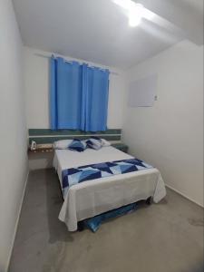 een slaapkamer met een bed en een blauw gordijn bij Apartamento em condomínio fechado na Farolândia in Aracaju