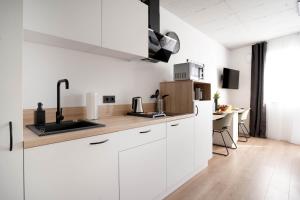 eine weiße Küche mit einem Waschbecken und einem Schreibtisch in der Unterkunft Schicke Apartments in Bonn I home2share in Bonn