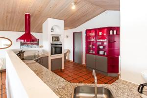 eine Küche mit roten Schränken und einem Waschbecken in der Unterkunft Thatched house with pool by the sea - SJ690 in Harboør