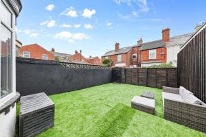 un patio con césped con 2 sillas y una valla en Luxury by the Sea, Beautiful 3 bedroom House with Fast WiFi, King Bed, Lovely Garden! Blackpool's Finest Getaway Experience for up to 8 Guests!, en Blackpool