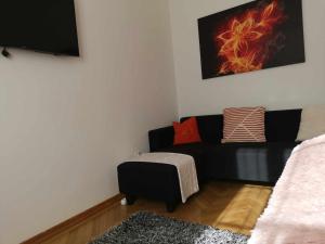 sala de estar con sofá negro y reposapiés en Eisenerzer Apartments - Radmeisterhaus, en Eisenerz