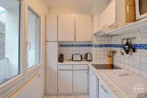 una pequeña cocina con armarios blancos y una ventana en Sourdillon/Hôpital Clocheville, en Tours