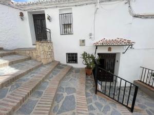 ein weißes Gebäude mit einer Treppe und einer Tür in der Unterkunft Casa María Martillo in Canillas de Aceituno