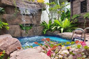 uma pequena piscina com uma cascata num jardim em Muchshima House em Bang Tao Beach