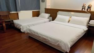two beds with white sheets in a room at Sow 斯佩洛 in Rende