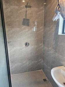 une douche avec une porte en verre à côté d'un lavabo dans l'établissement Modern Village Apartments, à Chipata
