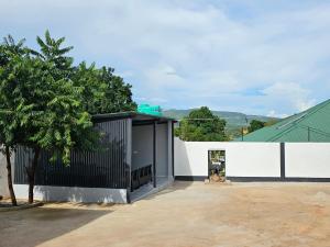 a house with a black gate and a tree at Modern Village Apartments in Chipata