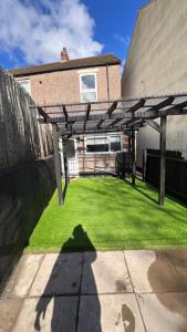 a backyard with a wooden pergola and green grass at 4 Bedrooms Homely House with Garden- Sleeps 9 Comfortably with 6 Comfortable Beds, Free Street Parking, Business Travellers, Contractors, & Holiday-Goers, Coventry, Near All Major Transport Links in Coventry and Motorway in Coventry