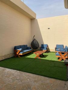 a patio with picnic tables and chairs on grass at شالية الفهد in Bawḑah