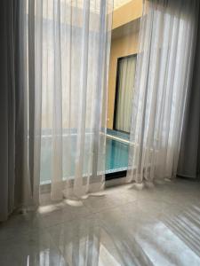 a room with a window with a pool and curtains at شالية الفهد in Bawḑah