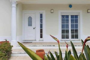 una puerta blanca de una casa blanca con plantas en Encantadora Vila perto Óbidos O Refúgio perfeito, 
