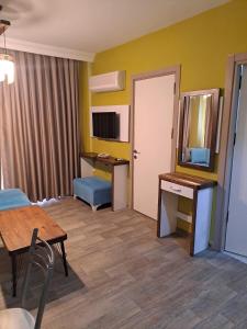 Zimmer mit einem Tisch, einem Schreibtisch und einem Spiegel in der Unterkunft EVLAND CiTY SUiT in Adana