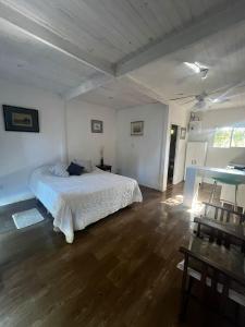 1 dormitorio con cama blanca y suelo de madera en Lodge Gloria en Dique Luján