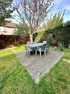 une table et des chaises sur une terrasse en bois dans la pelouse dans l'établissement Appartement calme avec jardin proche de Paris, à Évry-les-Châteaux