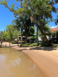 a beach with trees and a house and some water at Lodge Gloria in Dique Luján