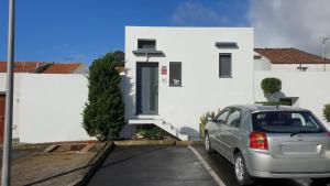 un coche aparcado frente a una casa blanca en Caminhos nos Levam pela Ilha, en Ponta Delgada