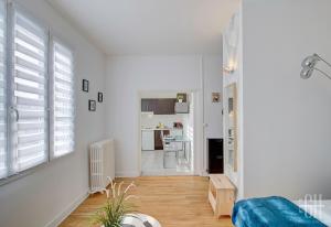 ein Wohnzimmer mit weißen Wänden, Holzböden und Fenstern in der Unterkunft Le Mirabeau 2 / Proche Gare in Saint-Pierre-des-Corps