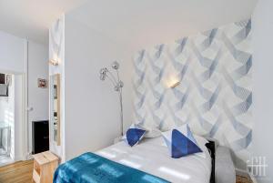 ein Schlafzimmer mit einem weißen Bett mit blauen Kissen in der Unterkunft Le Mirabeau 2 / Proche Gare in Saint-Pierre-des-Corps