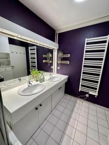 La salle de bains est pourvue de 2 lavabos et d'un mur violet. dans l'établissement Appartement calme avec jardin proche de Paris, à Évry-les-Châteaux
