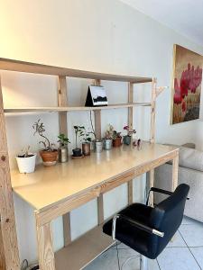 un bureau en bois avec des plantes en pot et une chaise dans l'établissement Appartement calme avec jardin proche de Paris, à Évry-les-Châteaux