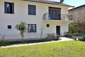 a white house with a balcony and a yard at Les Rosiers in Luchon