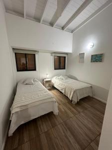 two beds in a room with white walls and wooden floors at Excellent apartment brand new in San Isidro
