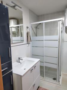 uma casa de banho branca com um chuveiro e um lavatório. em Breezy Beach Apartment em Sueca