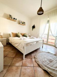 a white bed in a room with a large window at Carrie’s Home - Roma Fiumicino in Fiumicino