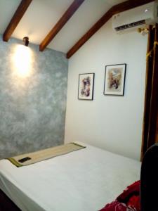 - un lit dans une chambre avec 2 photos sur le mur dans l'établissement Fajar Home Stay Batukaras, à Batukaras