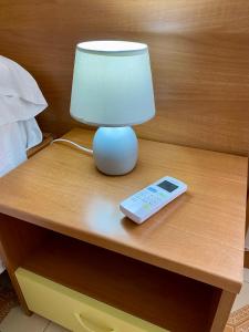 a table with a lamp and a remote control on it at Albergo Mendolia in Milazzo