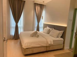 um quarto com uma cama com lençóis brancos e almofadas em AP Concept Hotel em Petaling Jaya