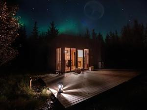 a cabin under the green northern lights at night at Buubble Hotel - Hrosshagi in Selfoss