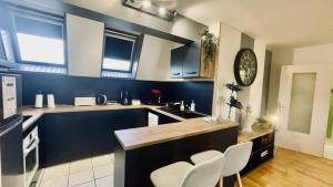 a kitchen with blue walls and white counters and white chairs at Bel appartement au coeur du quartier des artistes in Camaret-sur-Mer