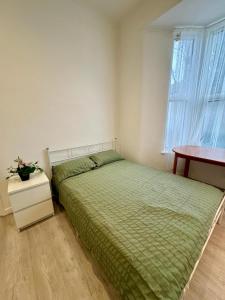 a bedroom with a bed and a table and a window at RELAKS LETTINGS in London