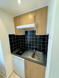 a small kitchen with a sink and black tiles at RELAKS LETTINGS in London