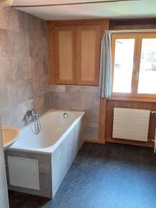 ein Badezimmer mit einer Badewanne und einem Waschbecken in der Unterkunft Chalet Bärenhaus in Sigriswil