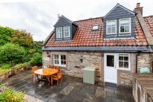 a stone cottage with a table and chairs on a patio at The Neuk 4 miles to St Andrews in Strathkinness