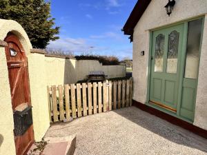 a house with a green door and a fence at Detached 3 Bed Cottage Mountain Views- Pets Wifi in Beaumaris