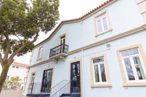 a white house with windows and a balcony at Surf & Sea Suites in Parede