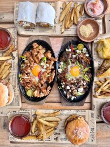 a table topped with plates of food and french fries at Outpost Beach Hostel in El Nido