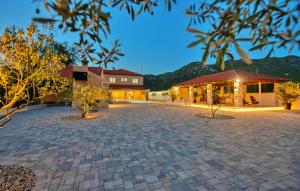 un gran patio con un edificio y árboles por la noche en Villa Zara with heated Hydromassage-Pool en Vrgorac