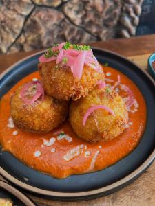 a plate of food with two meatballs and sauce at Outpost Beach Hostel in El Nido