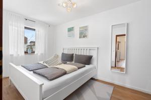 a white couch in a room with two windows at ANYTIME - Ferienwohnung Tina in Friedrichshafen am Bodensee in Friedrichshafen