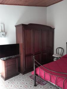 a bedroom with a bed and a large wooden cabinet at Antichi Sapori da Speranza in Gavoi